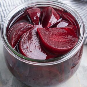 pickled beets in glass jar next to striped linen