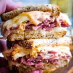 handheld stacked Reuben sandwich with sauce and melted cheese