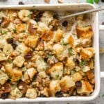 baked sausage apple stuffing in white baking dish with serving spoon