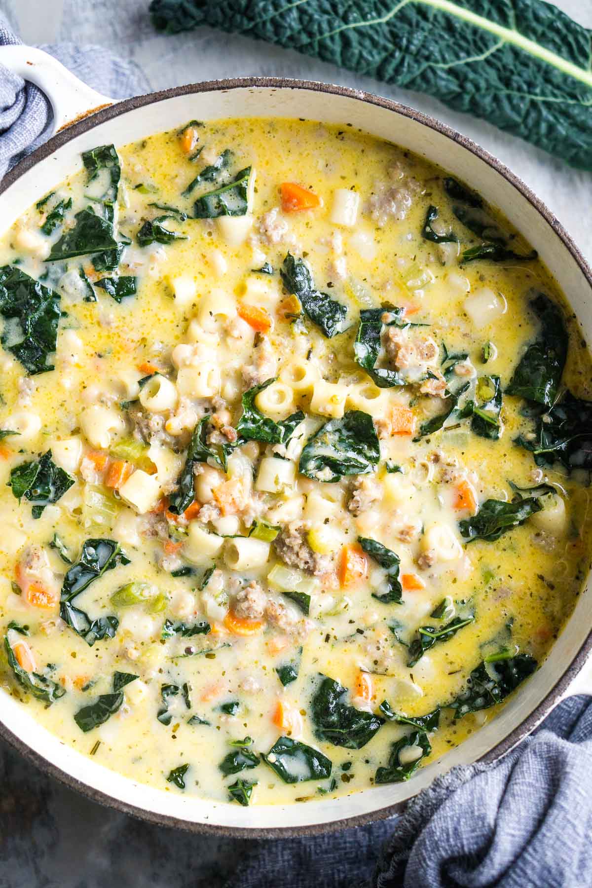 Sausage and kale white bean soup in white soup pot.