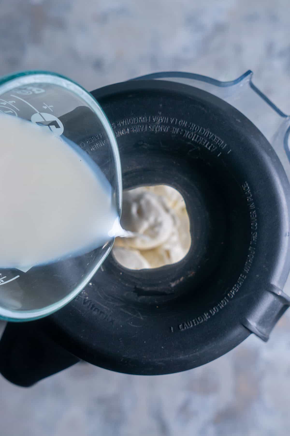 milk is being poured into blender with ice cream
