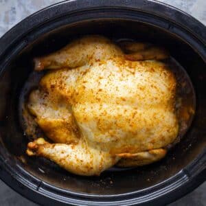Golden brown whole chicken in black slow cooker