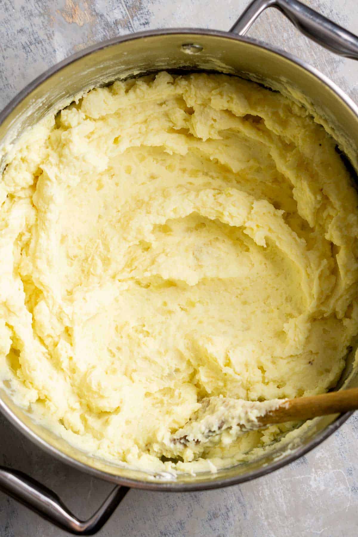 wooden spoon stirs mashed potatoes in the pot
