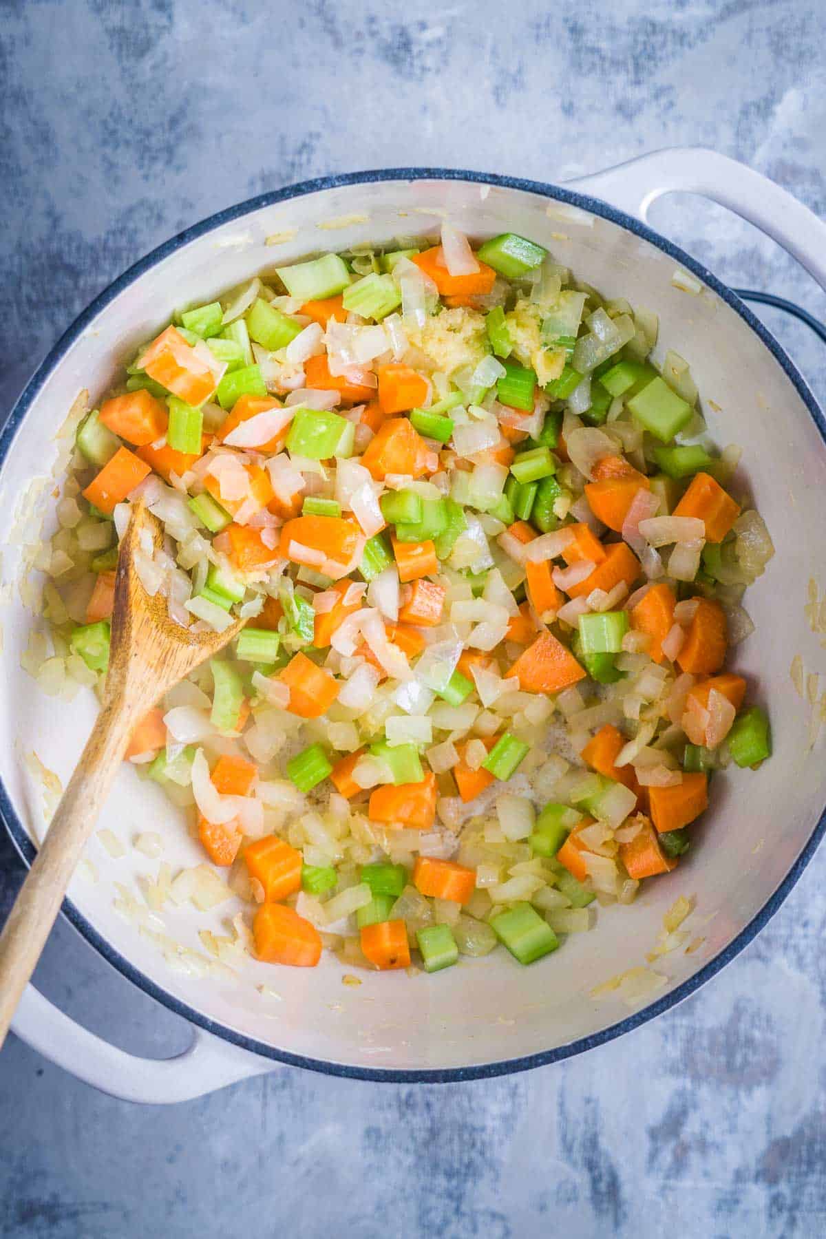 carrots, celery, and onions sauteing in white soup pot