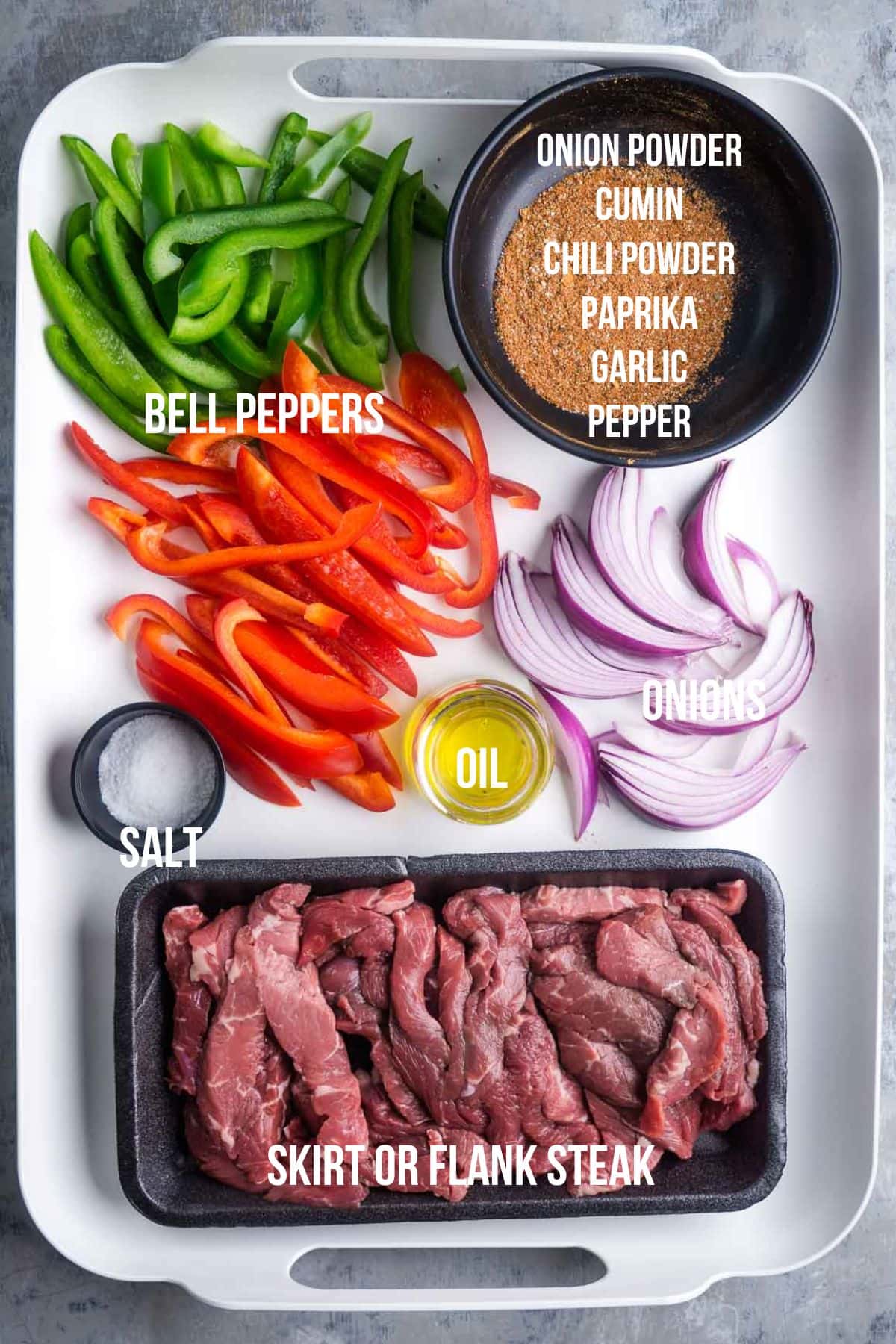 Labeled steak fajitas ingredients on white tray.