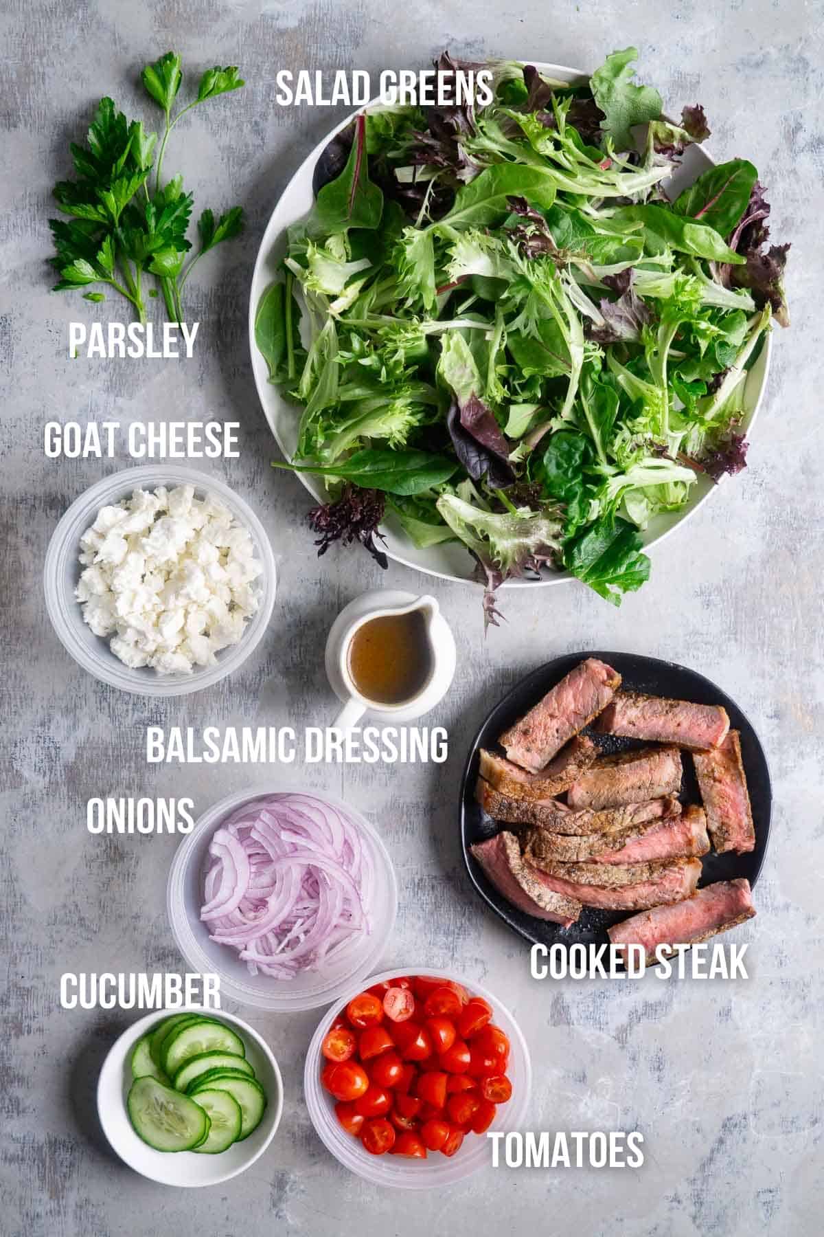 steak salad ingredients labeled in bowls ready for assembly
