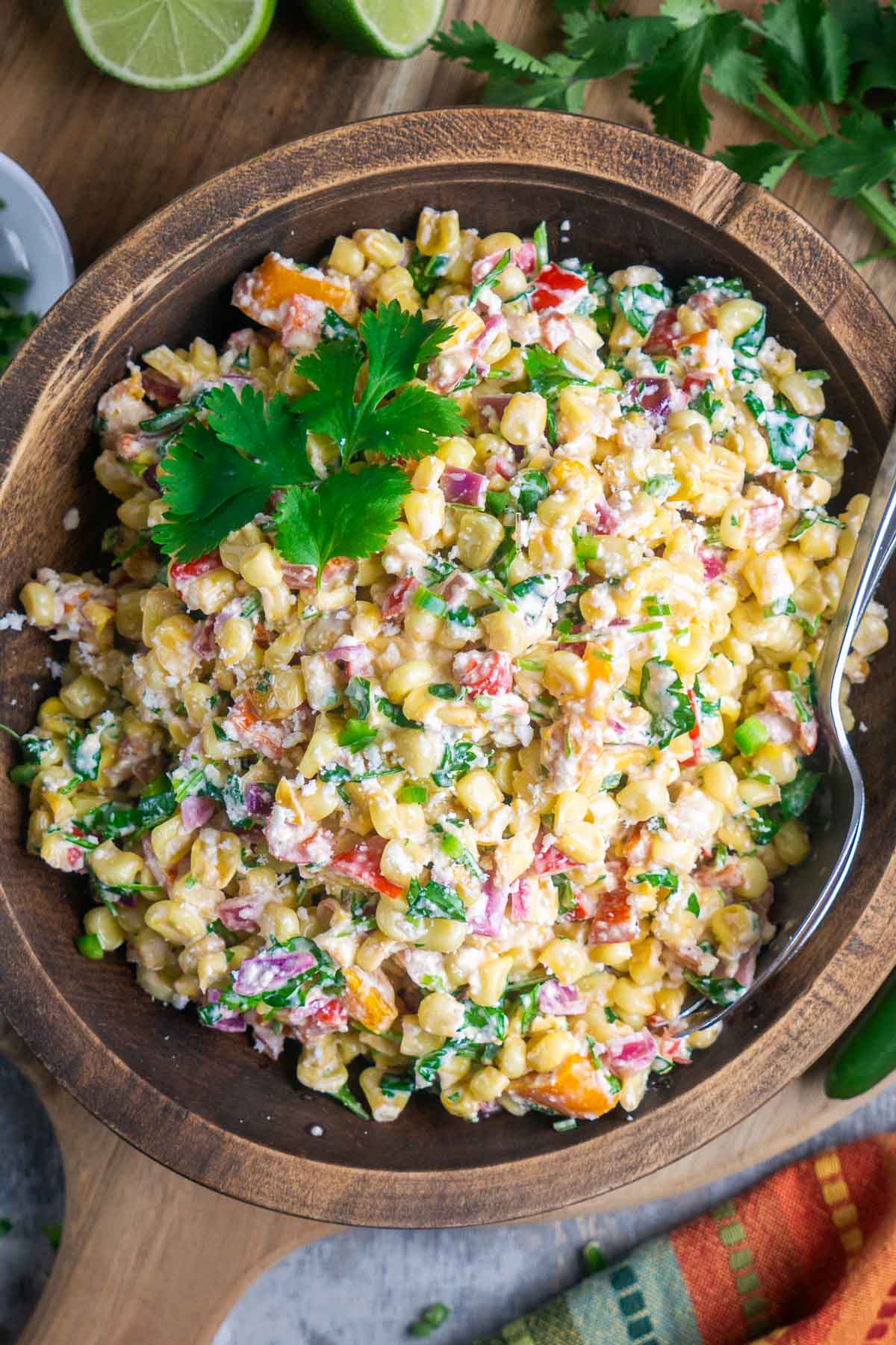 Street corn salad in brown serving bowl with serving utensils.