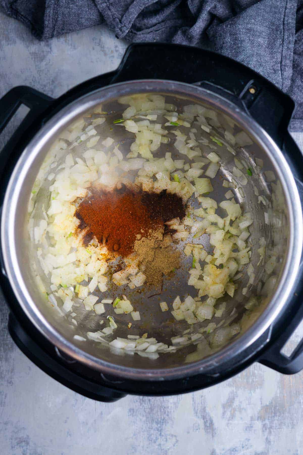 Onions and seasonings are sautéing in the instant pot for sweet potato chili