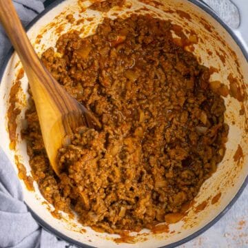 wooden spoon stirs cooked taco meat in skillet