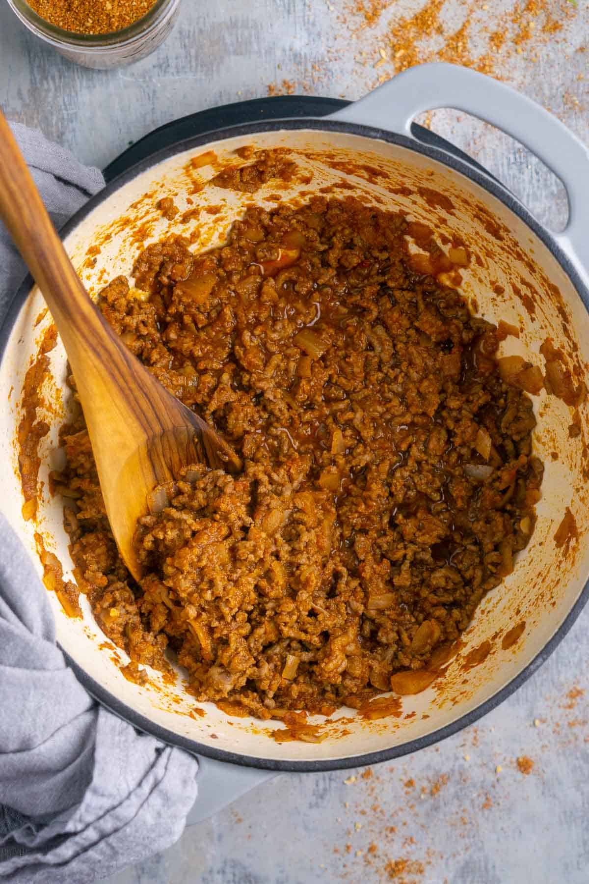 wooden spoon stirs cooked taco meat in skillet
