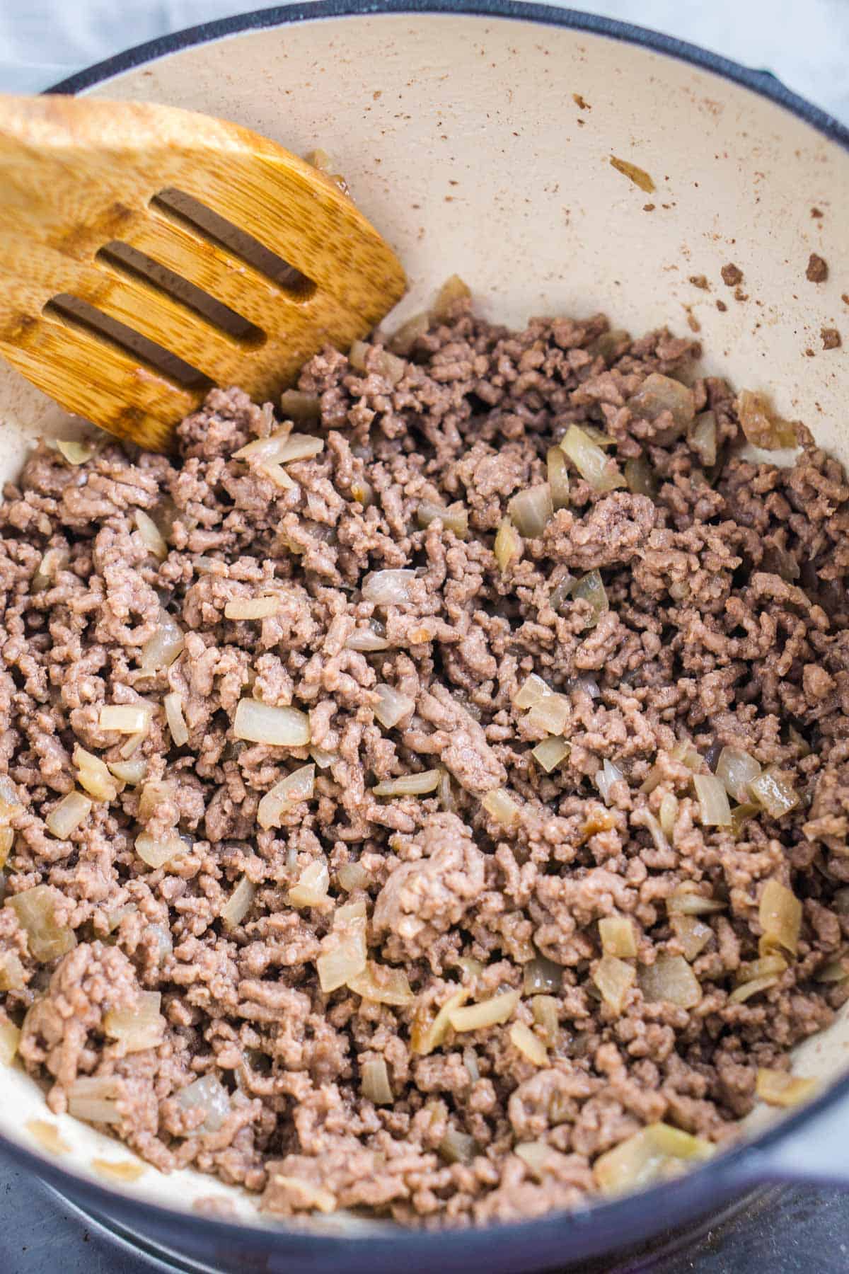 browned ground beef and diced onions in skillet
