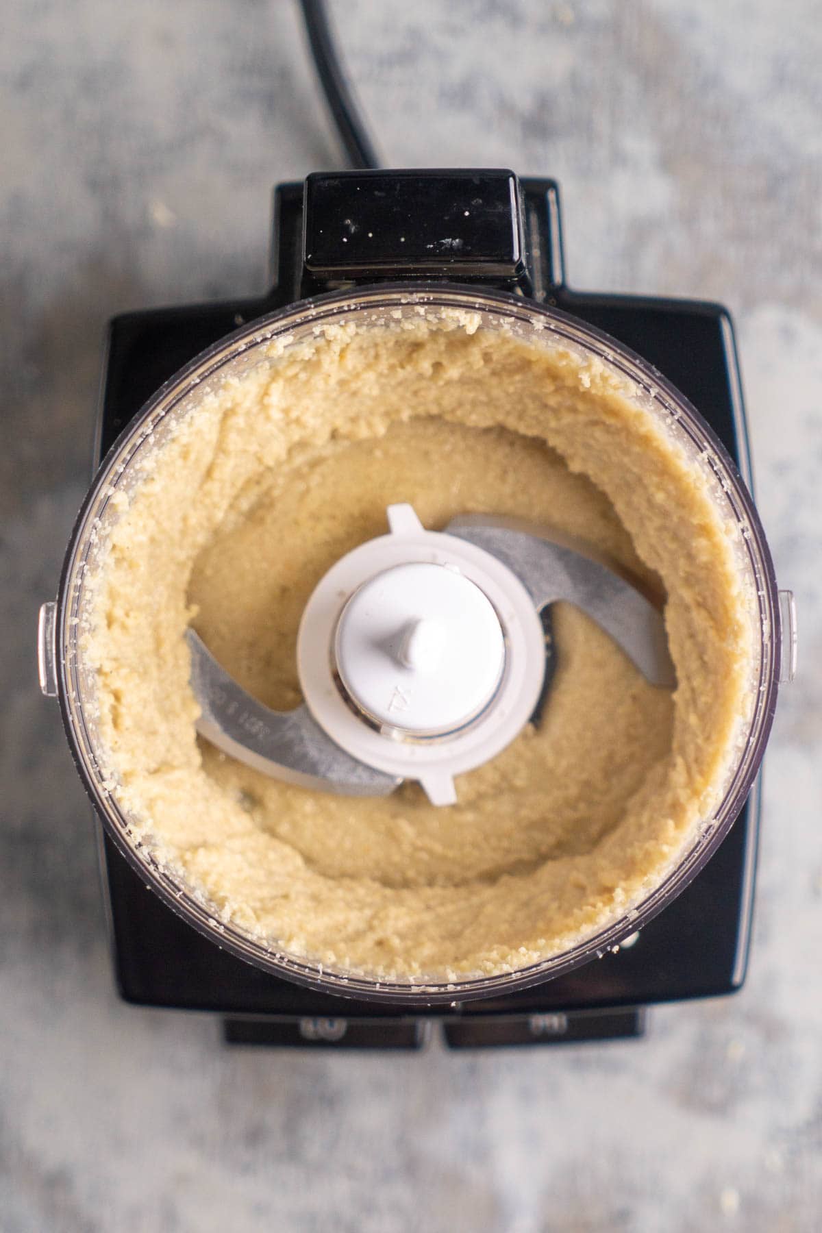 Top view of a food processor with partially blended sesame seeds.