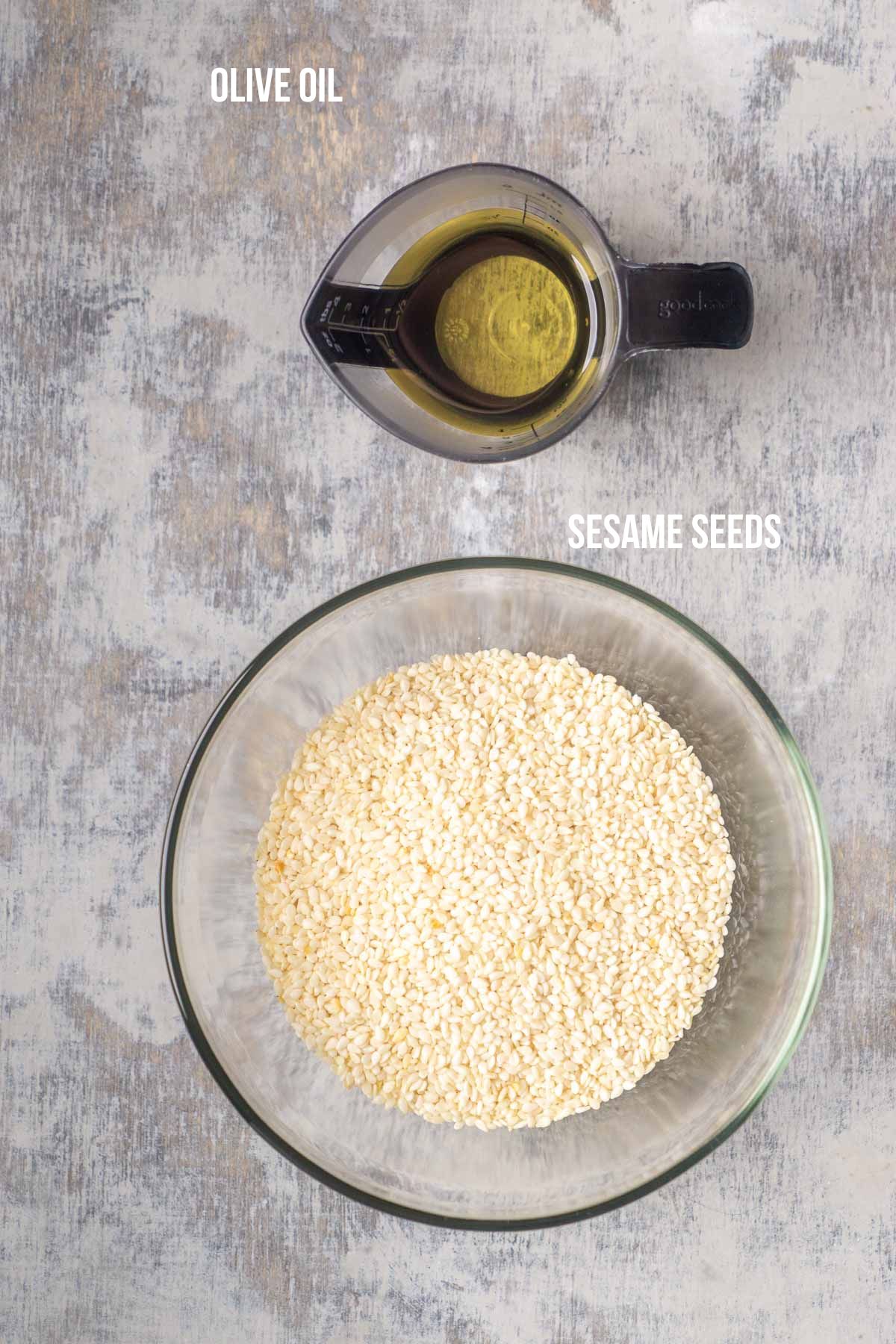 Olive oil and white sesame seeds on gray surface, each are labled in white text overlay.