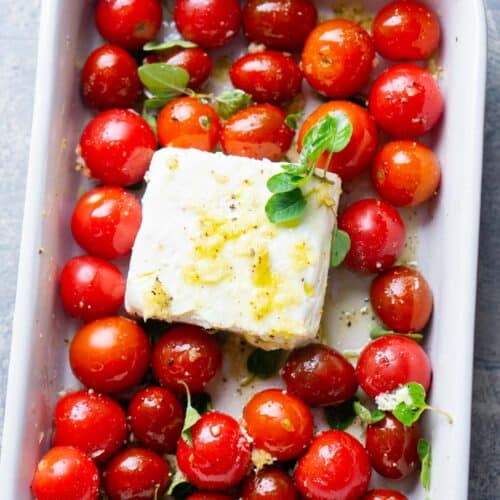 cherry tomatoes, feta cheese block, olive oil, and seasonings in white baking dish