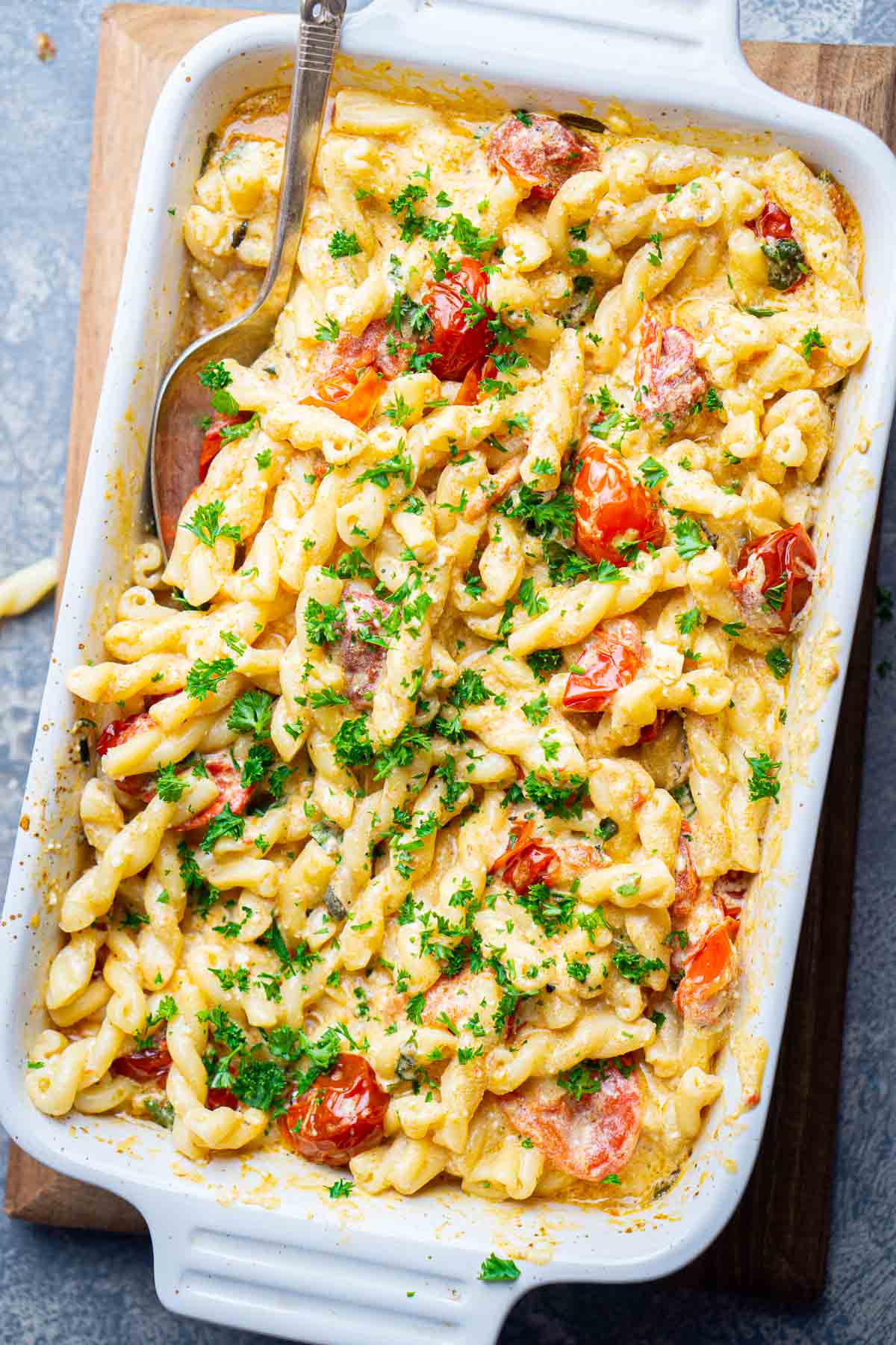 baked feta pasta in white baking dish with serving spoon