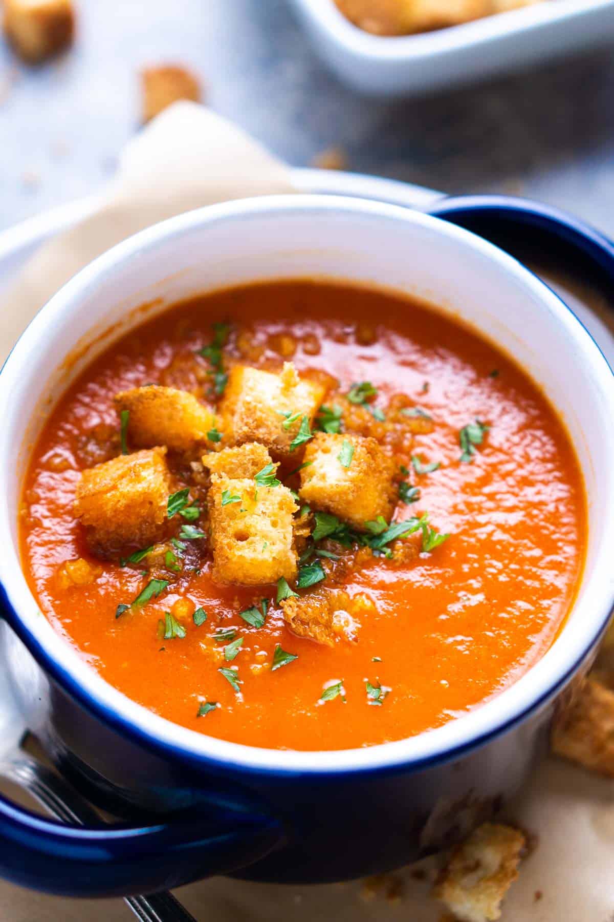 tomato soup in blue and white crock topped with croutons and parsley