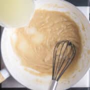 chicken broth is whisked in to roux in white saucepan