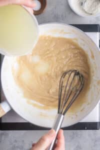chicken broth is whisked in to roux in white saucepan