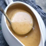 turkey gravy is ladled from white gravy boat