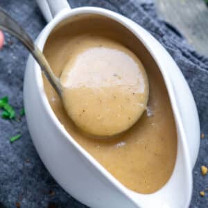 turkey gravy is ladled from white gravy boat