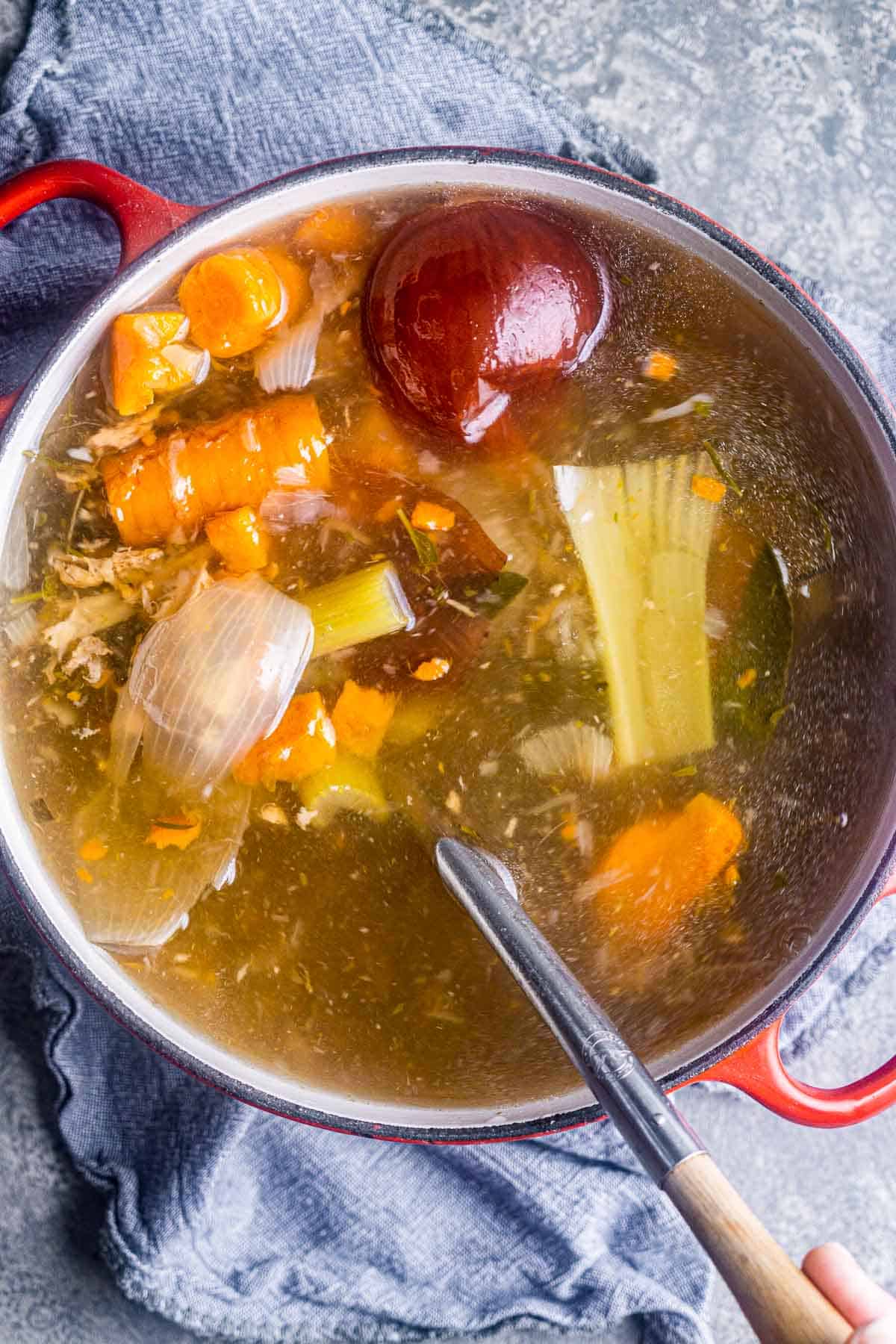 stock pot with turkey stock ingredients and soup ladle