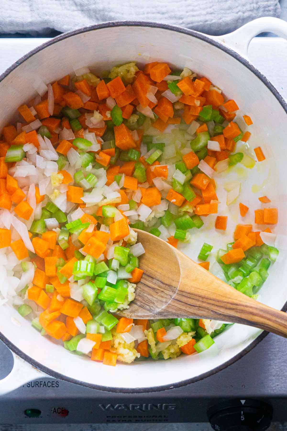 diced vegetables are stirred and sauteed in white dutch oven
