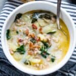 zuppa toscana soup in white bowl on striped linen