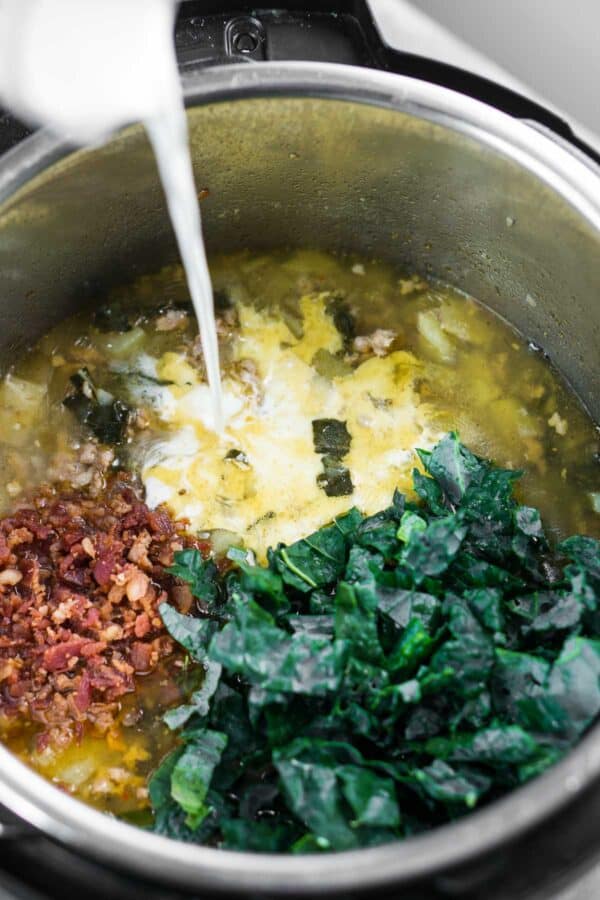Heavy cream being added to instant pot zuppa Toscana ingredients